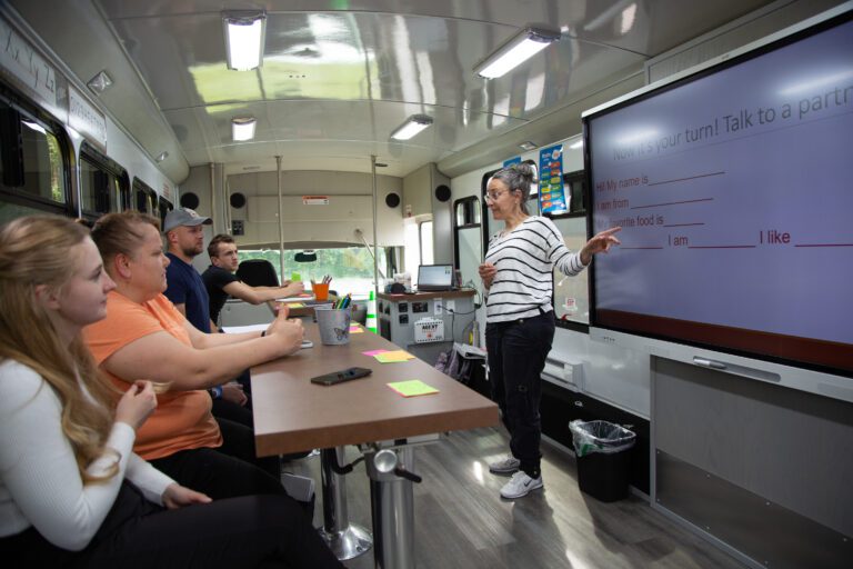 Lisa Brisbois, a language teacher, leads a class through basic conversation in English as she gestures to the screen.