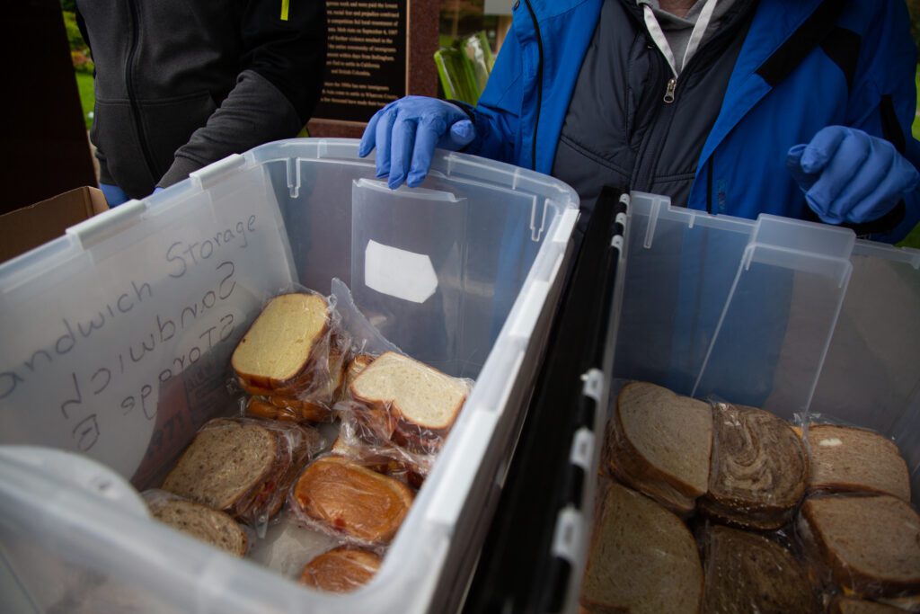 CAST hands out free peanut PB&J and cheese sandwiches from a storage bin.