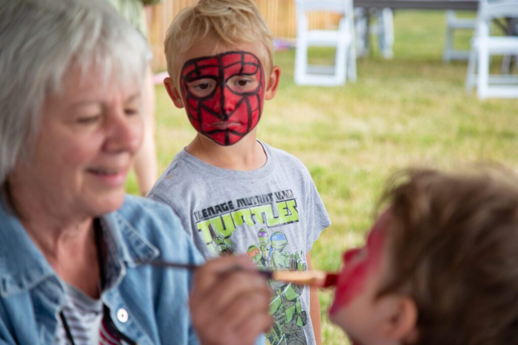 Elijah Wokich, 7, watches his brother Luka get matching Spiderman face paint.