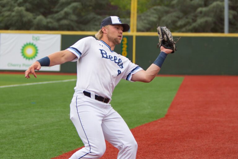 Bellingham Bells' first baseman Jack Van Remortel catches a fly ball as he leans backwards.