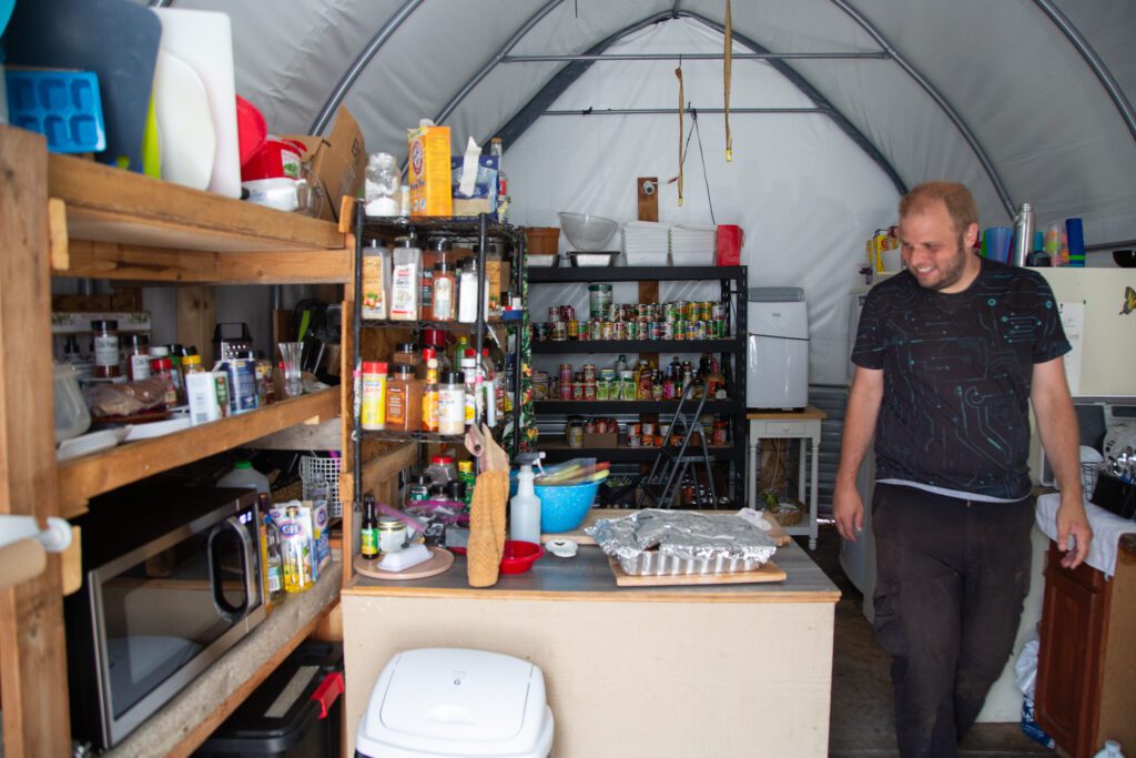 Unity Village chairman Douglas Gustafson walks in the shared village kitchen with shelves of spices.