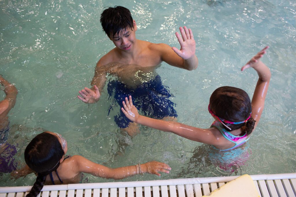 Nathan Chen offers high-fives to the young student swimmers.