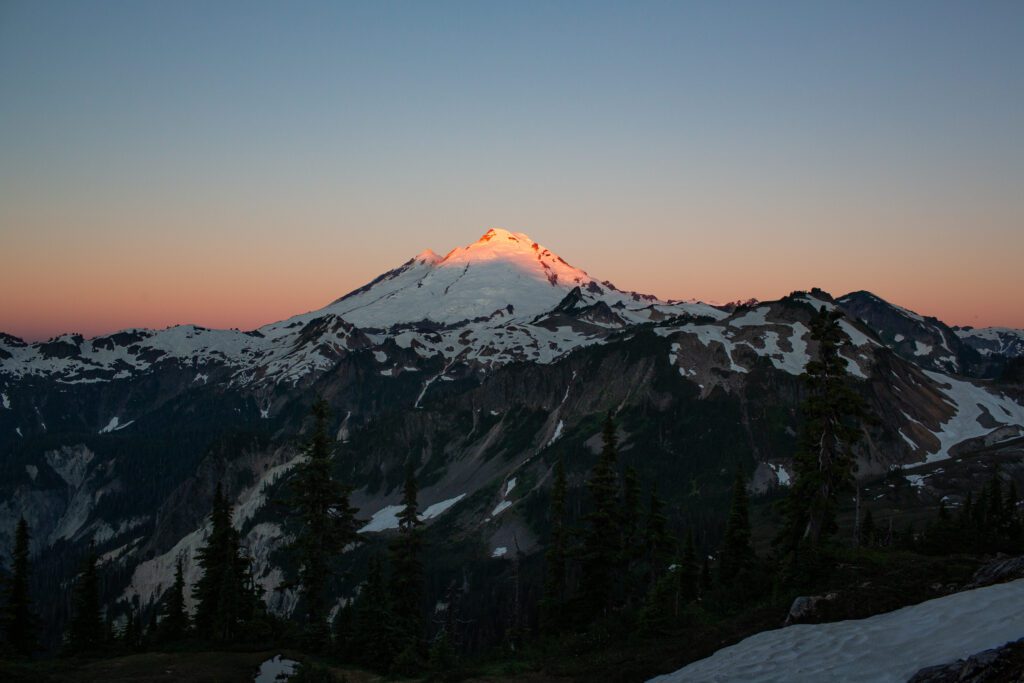 The rising sun shines an orange hue on the peak of Mount Baker.