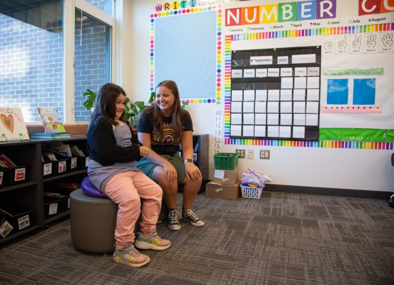 Kindergartener Claire Hagan, left, tries out a "wiggle seat" while getting a tour of her new classroom from teacher Kalli Kritsonis who is seated next to her.