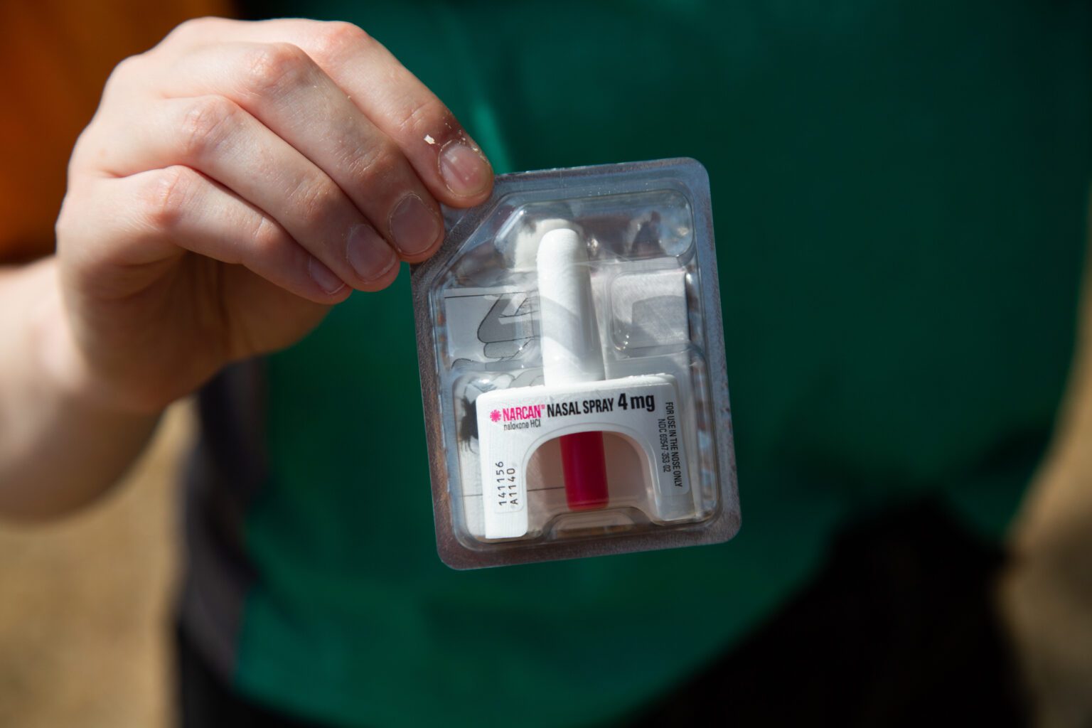 A person holds up a Narcan nasal spray.