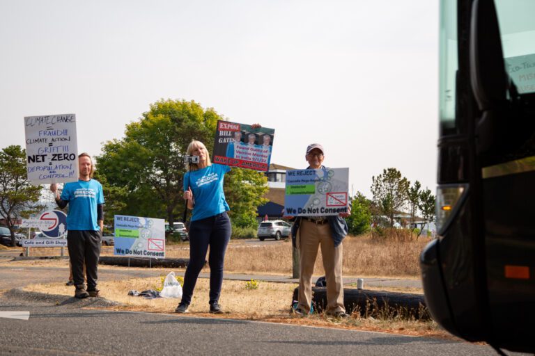 Protesters wave signs at an electric bus.