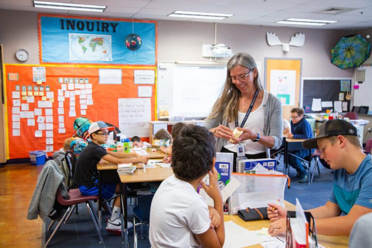 Fifth grade teacher Tawni Eisenhart passes out sticky notes to the seated students at the start of an activity.