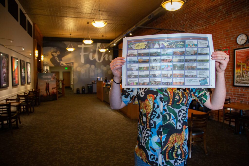 Projectionist Skyler Hunt holds the Doctober schedule up in the lobby of the Pickford Film Center.