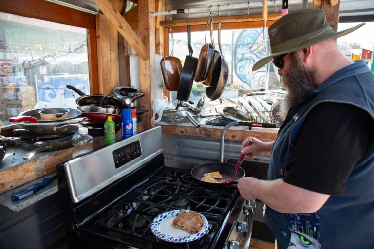 Unity Village resident Nathan Seims cooks eggs and hash browns with donated food in the communal kitchen.