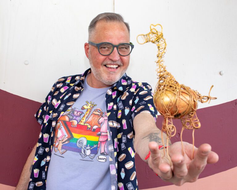 Kevin Coleman holds up a rock turned giraffe statue outside of WinkWink.