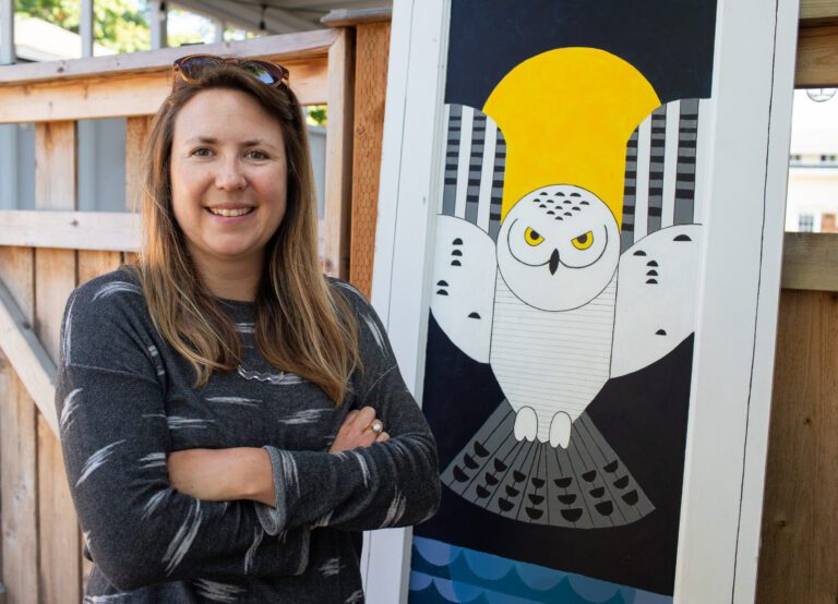 Artist Kirsten Anderson stands with her stolen door with an owl design.