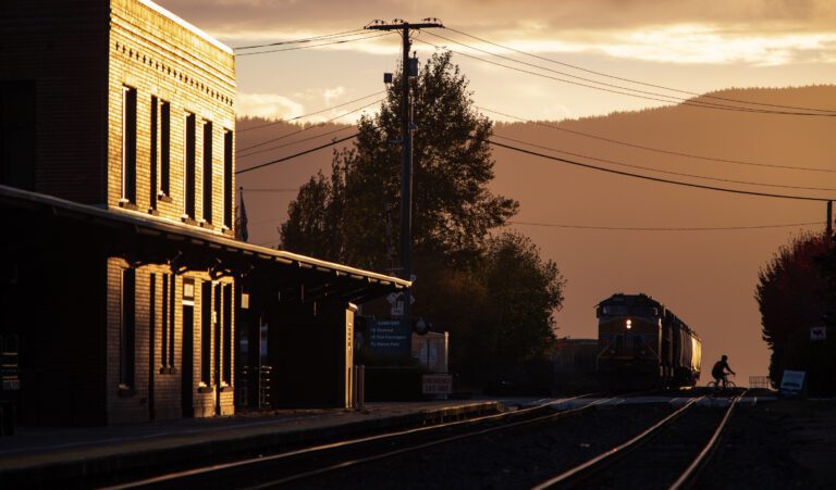 A biker crosses the railroad tracks outside the Amtrak station as shadows cast from the sun setting.