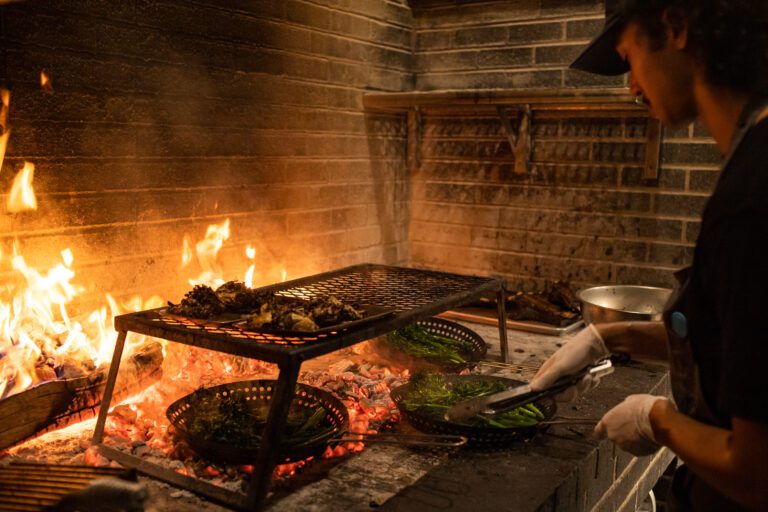 Jared Jones roasts broccolini and meat over coals on a wood fire at Carnal.