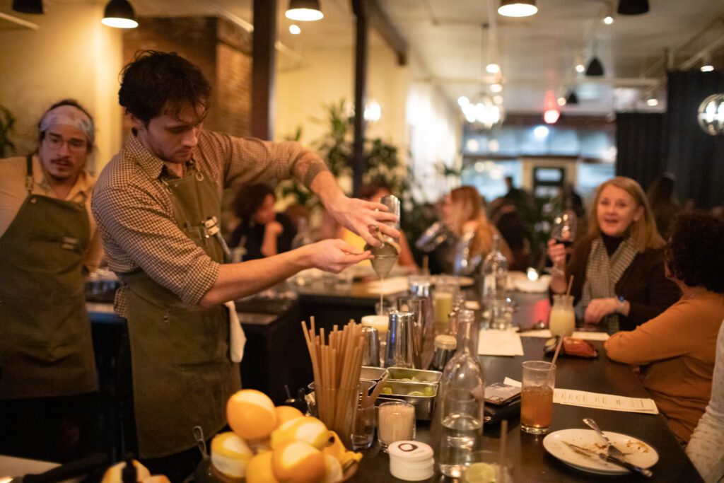 Bartender Robbie Hagan pours a drink at the bar in Carnal with a packed room.