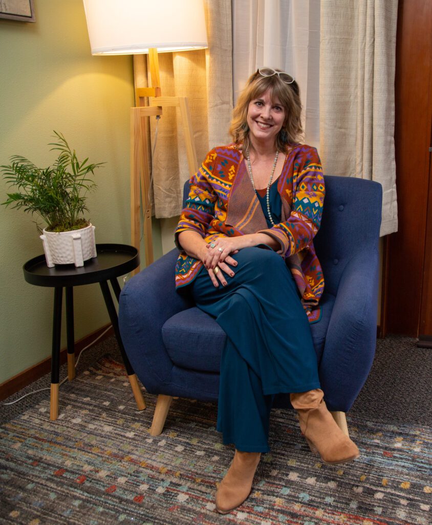 Karen King sits on a blue couch with a smile.