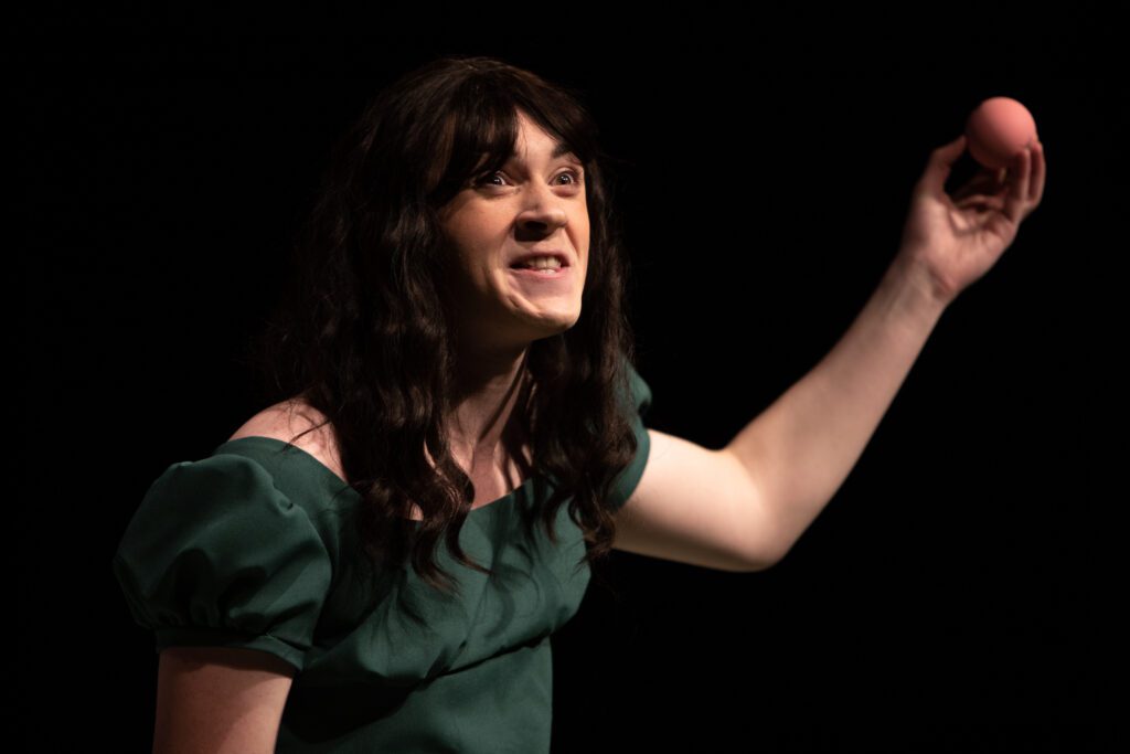 Mary Bennet (Aidan Ramey) makes an expression while holding up a ball.