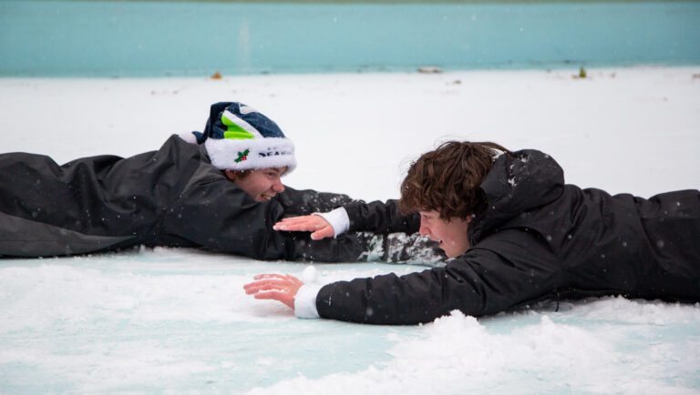 Camden Austin, left, and Benji Mills slide through the snow while holding onto each others arms.