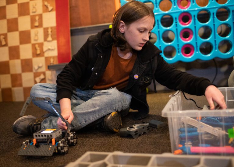 Robert Prentice works on building an arm of a robot on the floor of the Bellingham Coding Club.