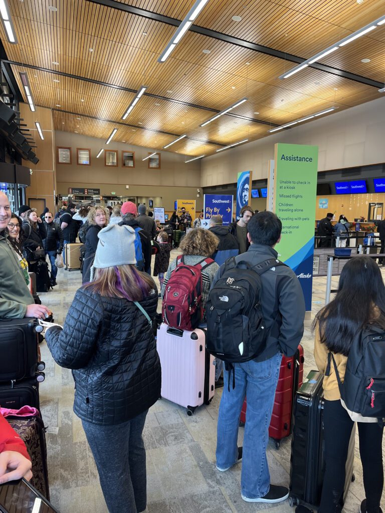 Passengers queue up for baggage check in the crowded airport.