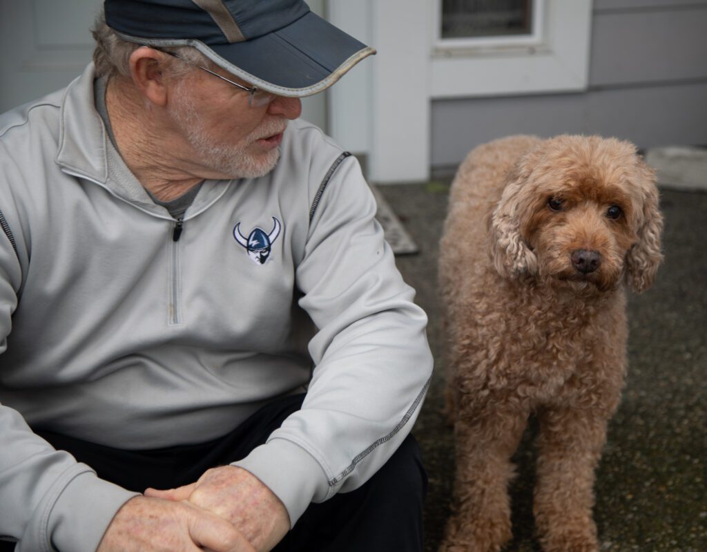 Pee Wee Halsell sits on his front porch with his fluffy dog Sydney.