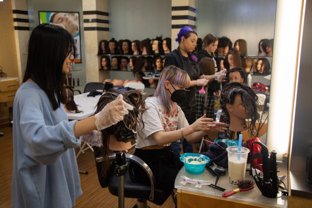 From left, Faith Silan, Forest Keeth and Keesha Vinnie practice conditioning hair on mannequins.