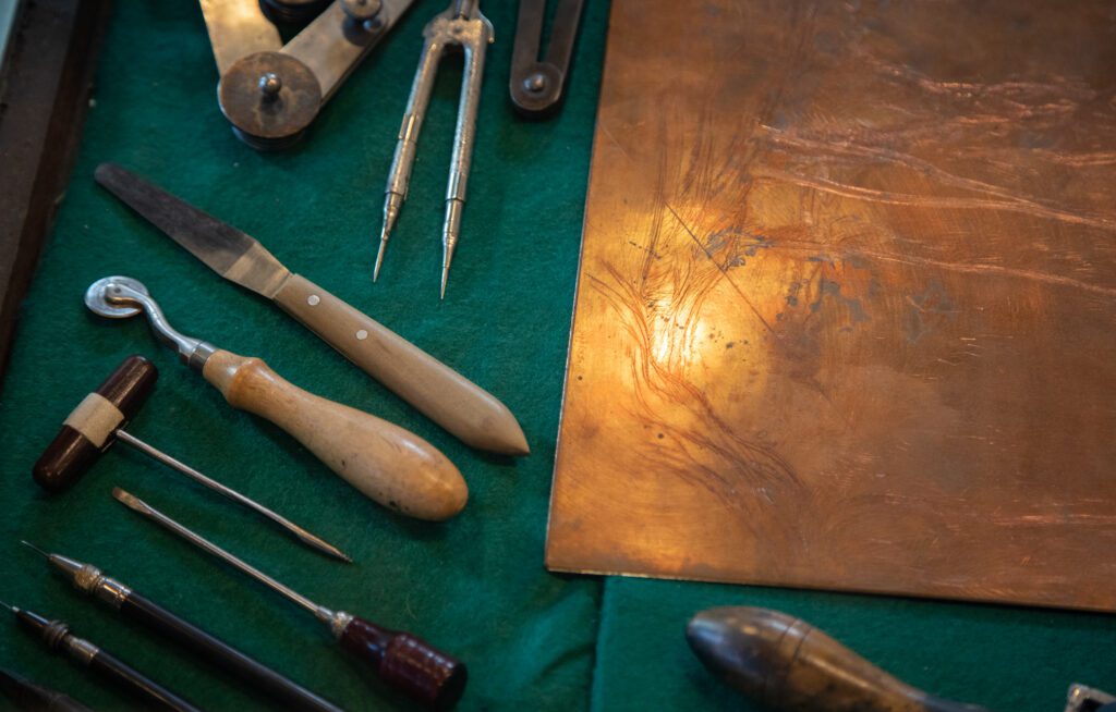 Tools laid next to a copper plate.