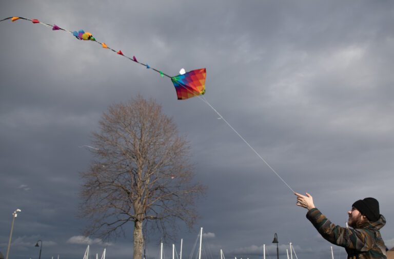 Octavious Bass flies a kite towards the dark cloudy sky.