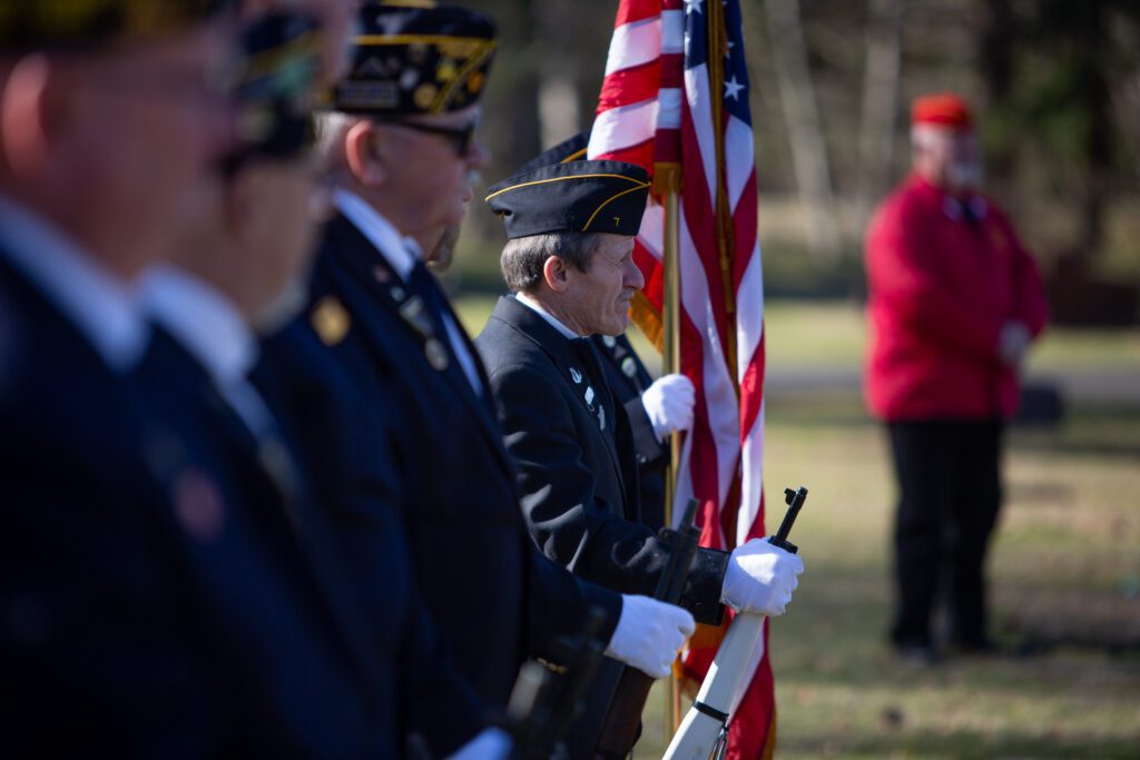 The American Legion Post 7 honor guard holds guns and the American flags.