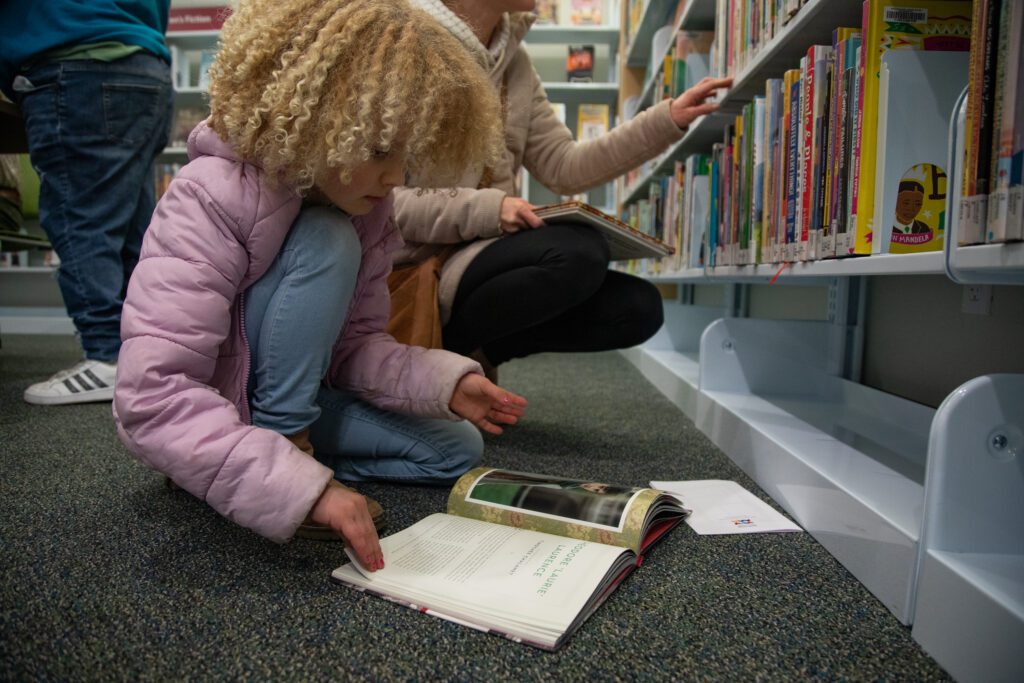 Ava Bradley, 6, reads a book on the ground.