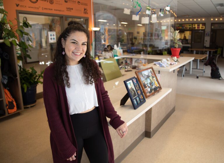 Ronnie Delgado, who works at the Max Higbee Center in Bellingham, smiles from inside the store.