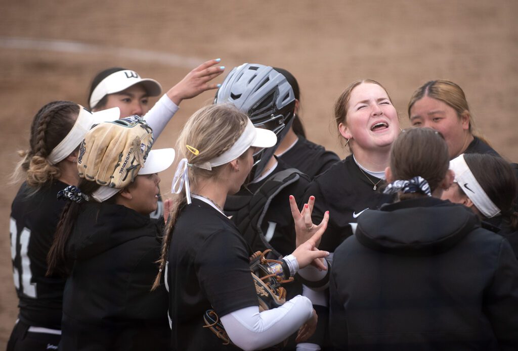 Western senior first baseman Brooke Fesenbek celebrates with her teammates in a close huddle.