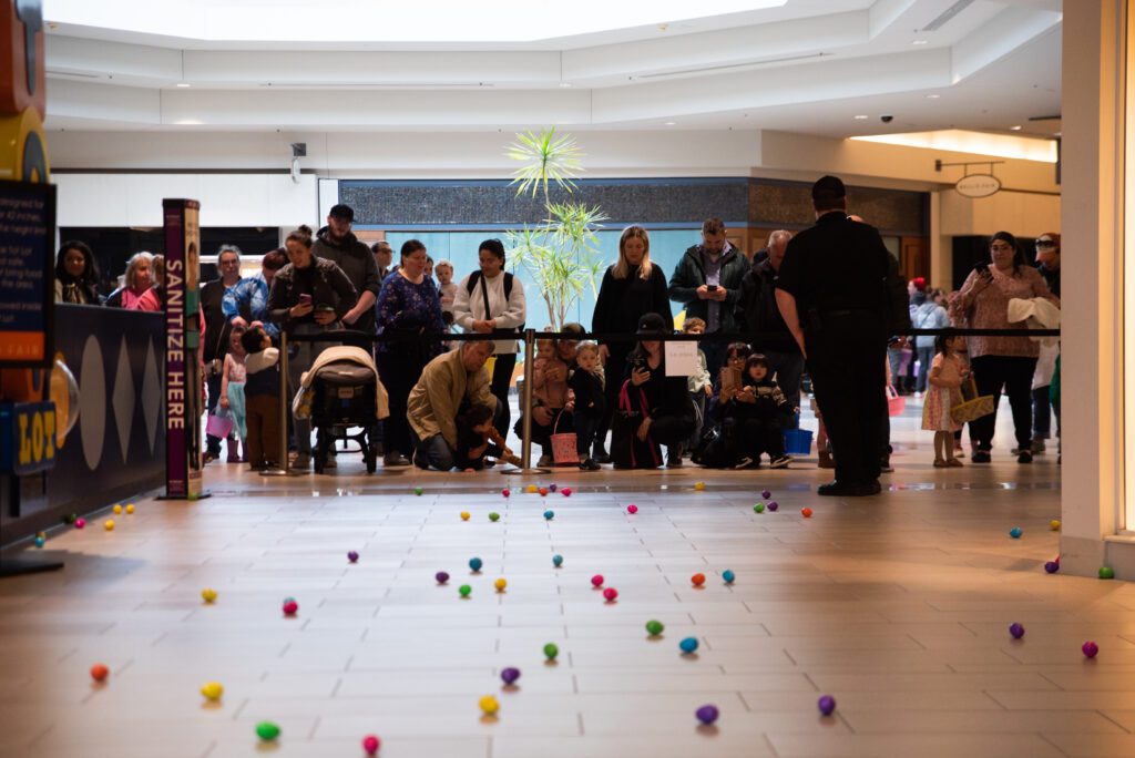 Children wait with their baskets for the Easter egg hunt to begin from behind a barrier.