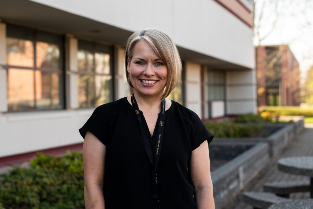 Laura Lupo, Meridian School District's mental health coordinator, smiles next to the school's building.