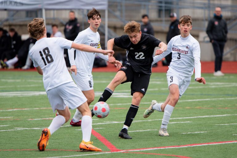 Bellingham junior Judah Straight kicks the ball while surrounded by other players.