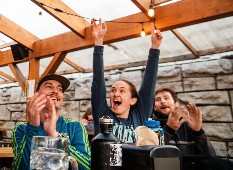 Kraken fans at Schweinhaus Biergarten raise their arms and clap.