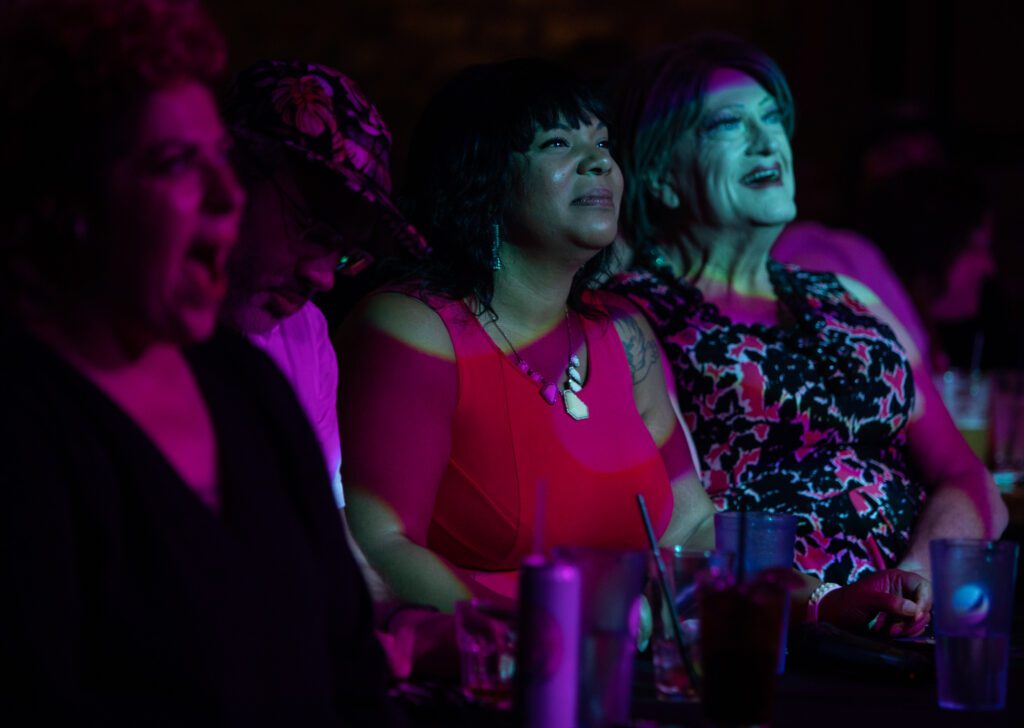 From left, host Rebecca Quirke and judges Alex Bruner, Kristina Michele Martens and Betty Desire watch performances for Bellingham Idol as bright lights shine over the audience.