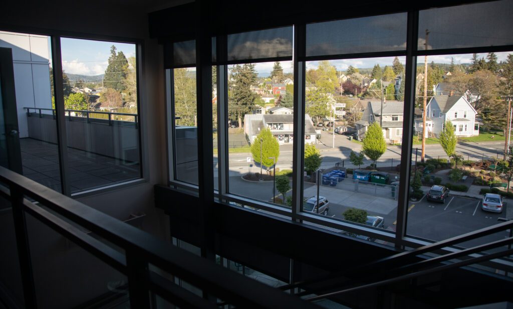 Outside the Eleanor Apartments windows, there are cars parked near the recycling and garbage area.