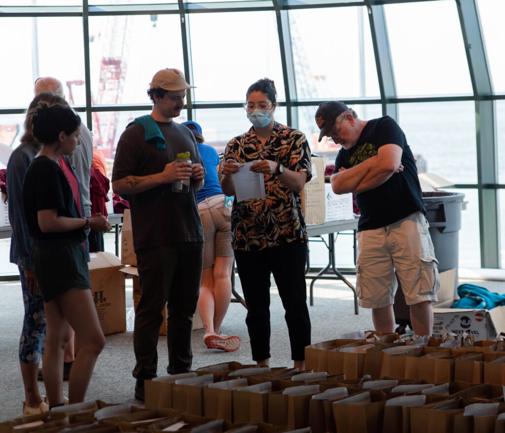 Volunteer Coordinator Sarah Beck, center, gets volunteers oriented as they chat near the bags of items.