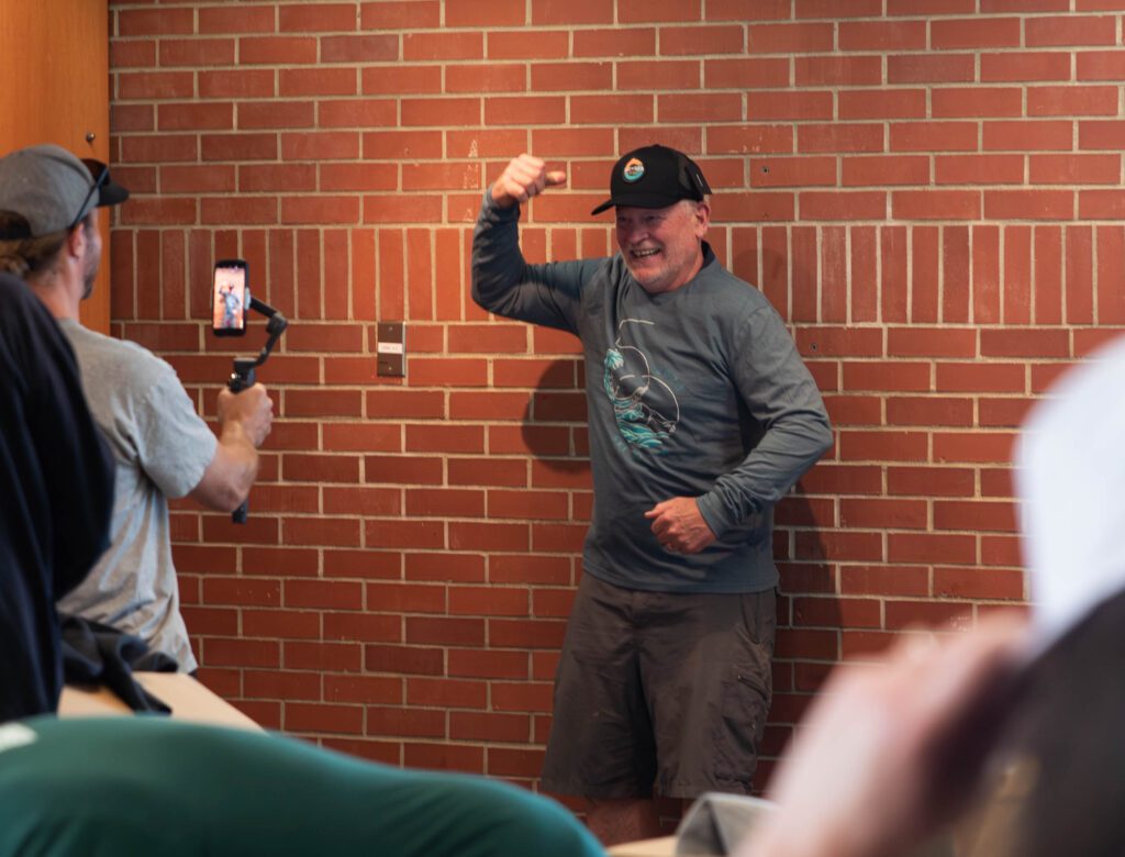 Cliff Knitter, one of the finish line chairs, strikes a pose in front of a person recording him with a phone.