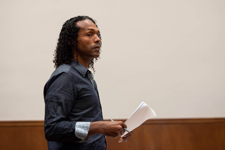 Joel Johnson holding a stack of paper and a pen.