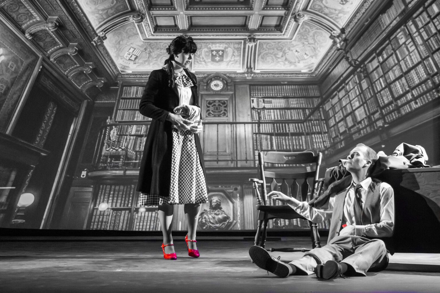 Lily Larson as Dorothy dazzles in red heels as she talks to Jack Straw in a black and white scene.