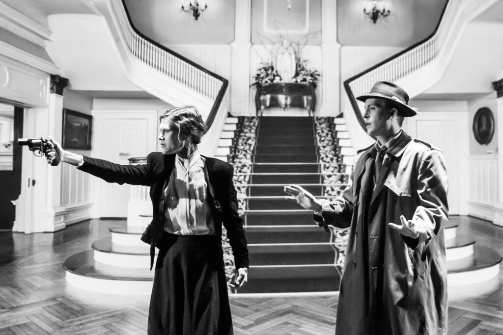 Virginia Wawner as Esme West confronts Dorothy offstage with a gun while Kris Erickson as Jack Straw looks on.