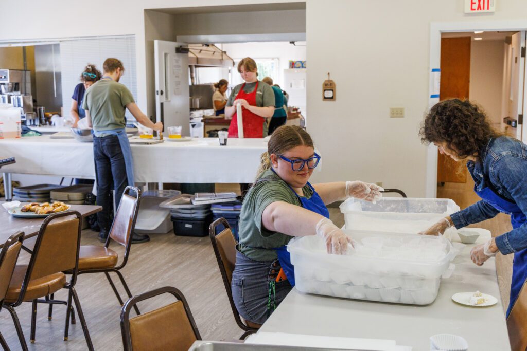 Volunteers Alida and Elizabeth Morgan, right, powder kourabiedes cookies and then put them in storage containers as others help in the kitchen.