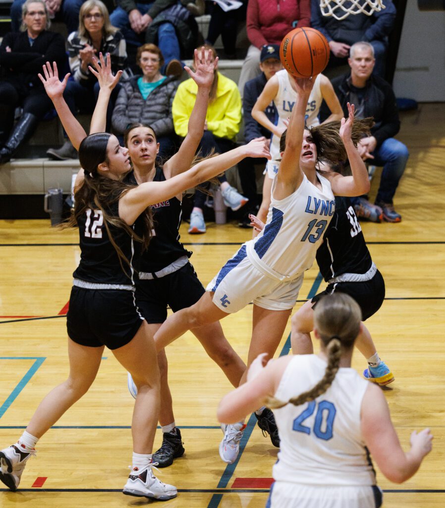 Lynden Christian’s Grace Hintz gets past the defense as she dives to make a shot past the raised arms.