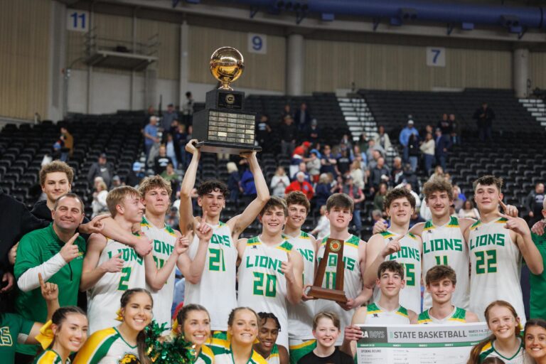 Lynden players, coaches and cheerleaders celebrate after Lynden beat Mark Morris while holding up their trophies and awards.