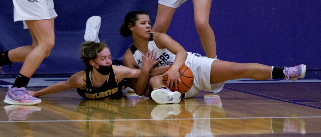 Nooksack Valley’s Tehya Moore battles for a loose ball with a Burlington-Edison defender on the basketball court floor.