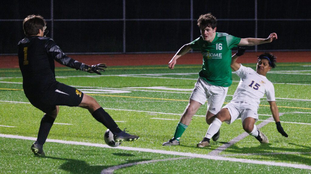 Ferndale's Josh Ruble stops a kick by Sehome’s Hayden Longwell as a defender fails to block the shot next to him.