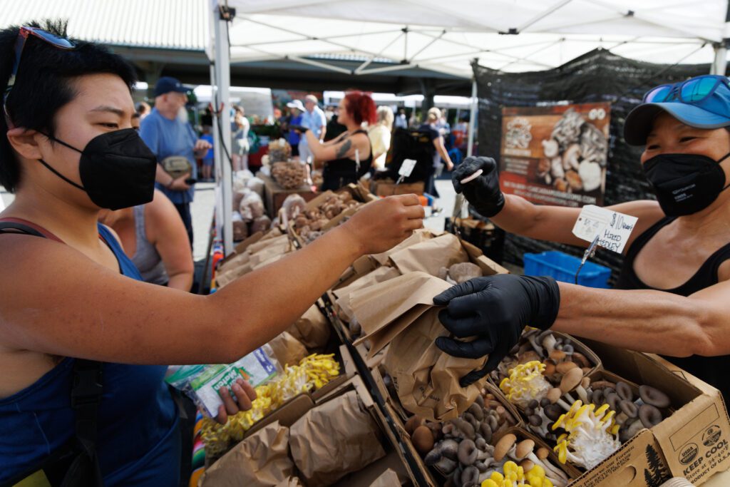 Olivia Ng, left, uses SNAP dollars to buy mushrooms from a vendor.