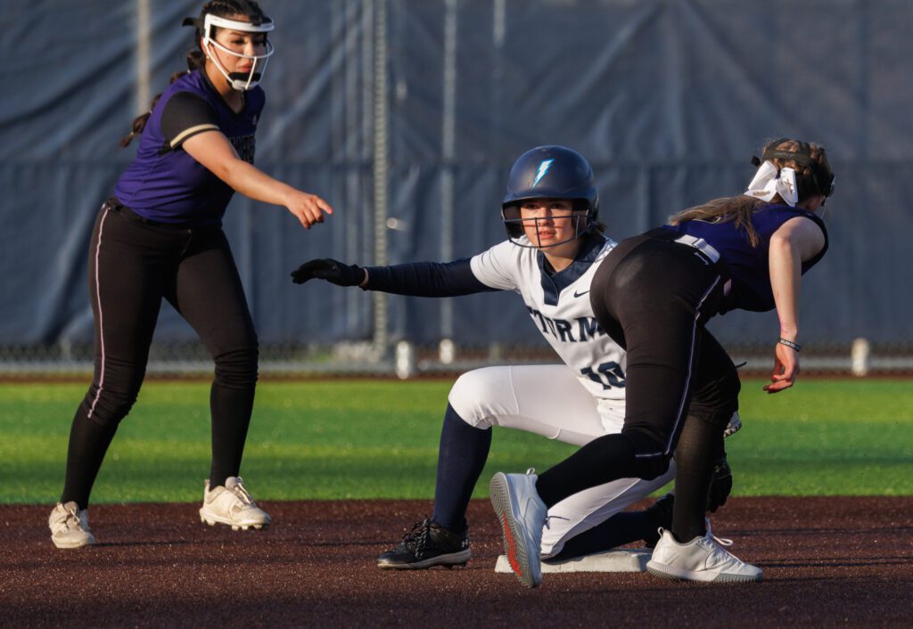 Squalicum's Aili Vroman slides safely into second base as Oak Harbor players try to get the out call from the umpires as she kneels on the plate.