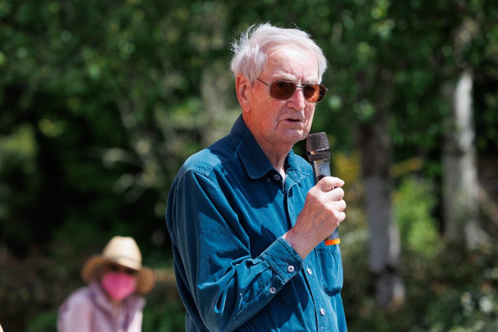 Explaining how his farm came to fruition, Bob Barker talks to guests with a microphone in hand.